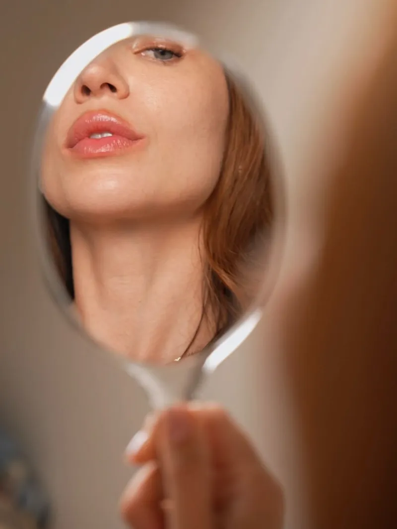 Femme observant son visage reposé dans un miroir